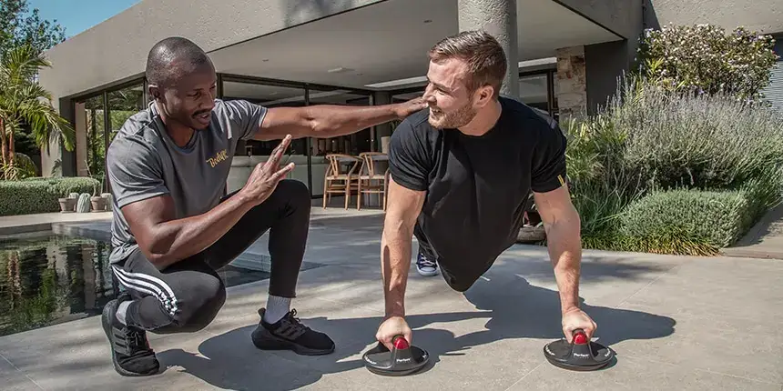 Client doing high intensity interval training with a personal trainer at home